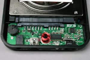 Abbildung 1: Das kleine Innmax-Bauteil rechts von der Magnetspule arbeitet als RFID-Decoder, USB-SATA-Brücke und AES-Chip.