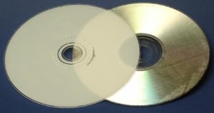 Abbildung 1: Eine DVD besteht aus zwei Scheiben, die einfach aufeinander geklebt werden – deutlich sind die Kleber-Spuren auf der Daten-Scheibe (rechts, silbern) zu sehen. Insgesamt ist die DVD dann so dick wie eine CD